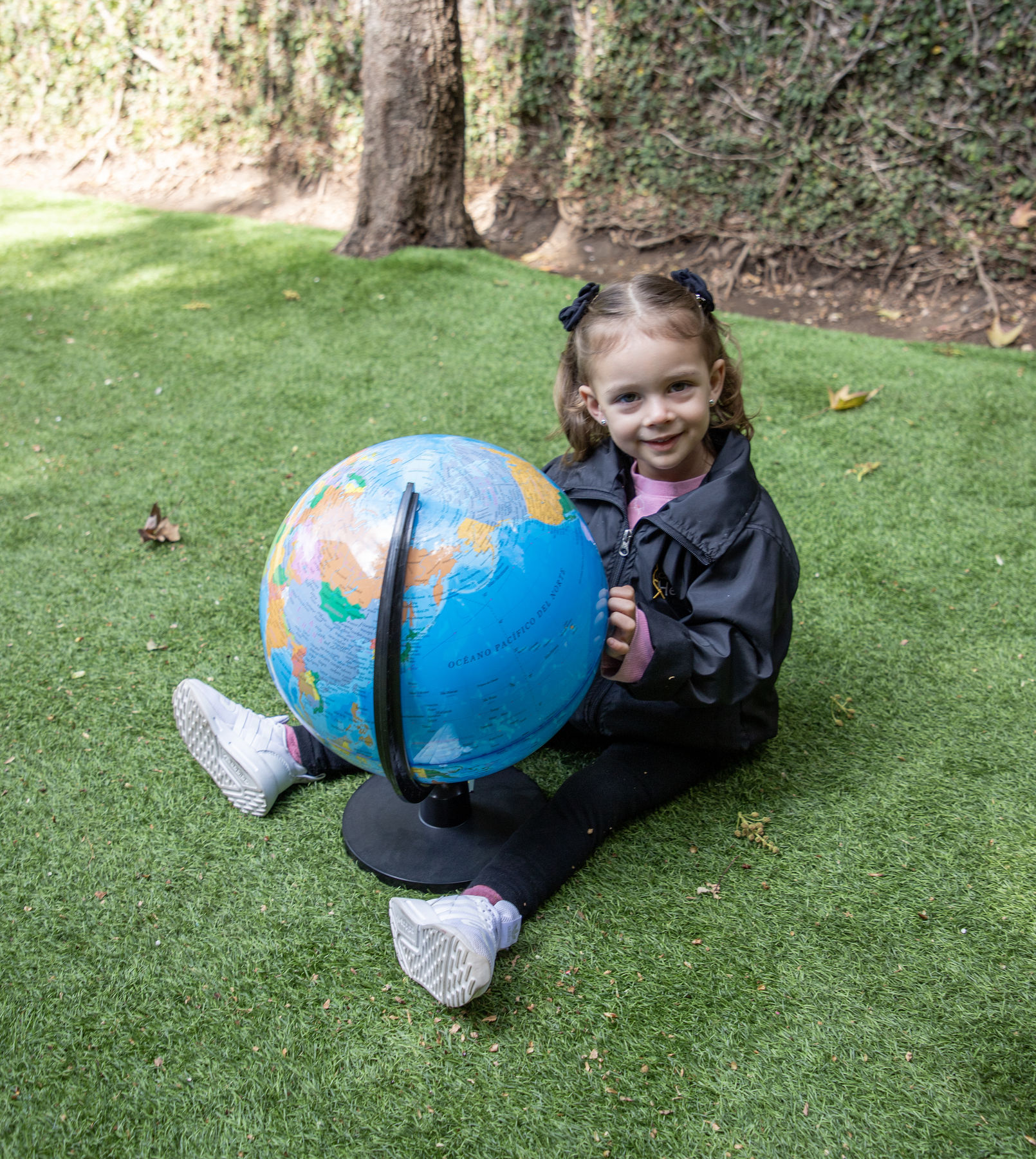 Alumna de Colegio Hélice con un globo terráqueo en el jardín