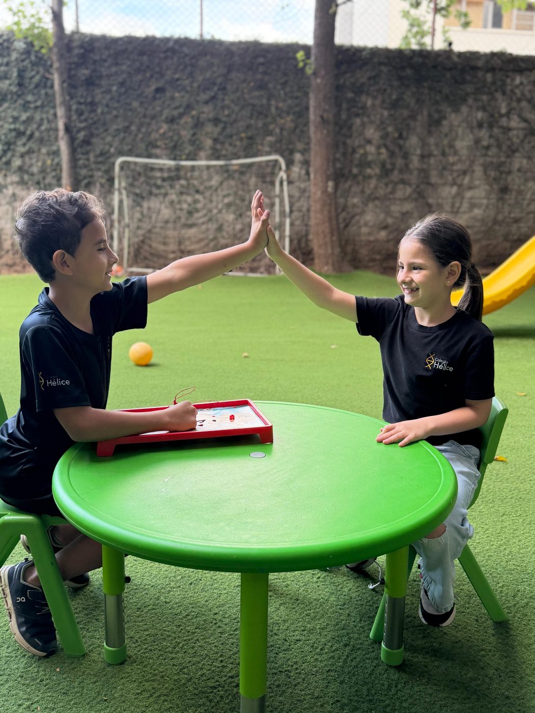 Dos alumnos de Colegio Hélice chocando las manos en el jardín