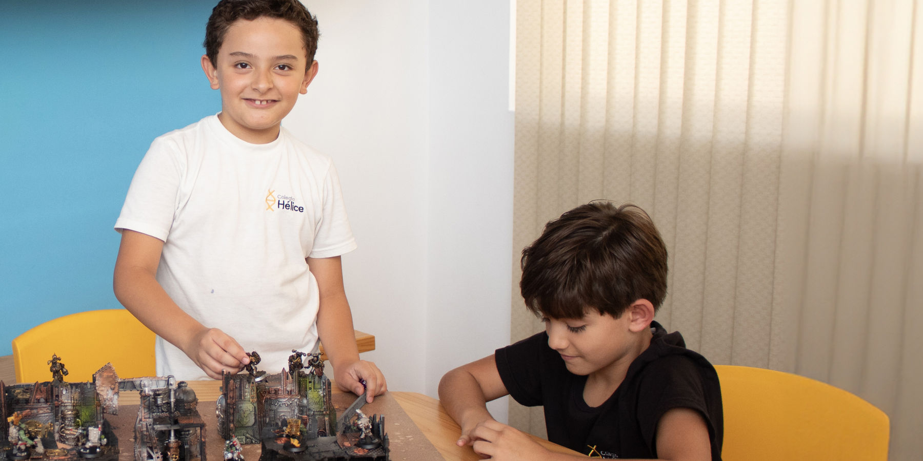 Dos alumnos de Colegio Hélice construyendo un escenario de juego de mesa en el aula